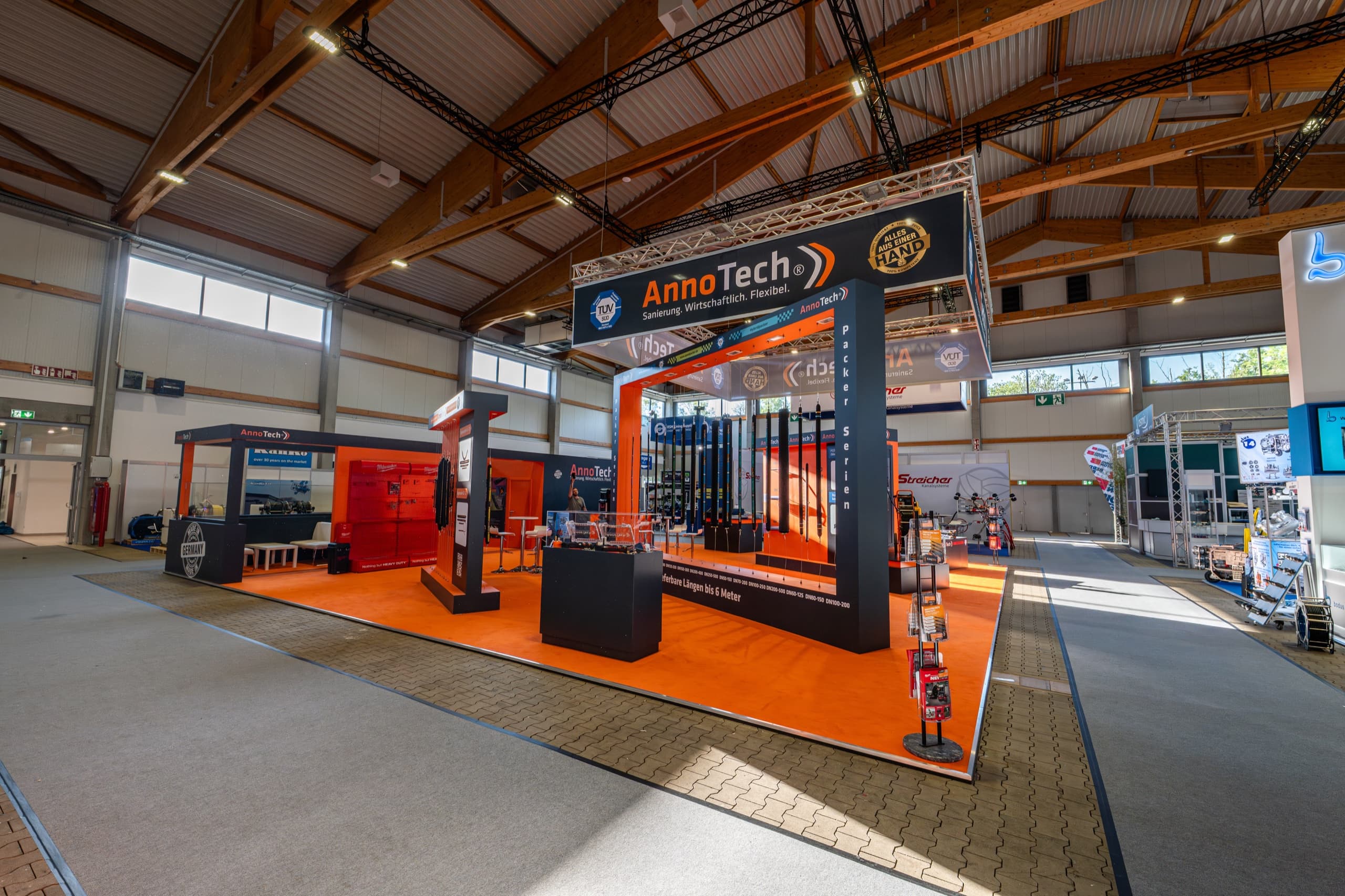 AnnoTech Messestand in Messehalle, Vogelperspektive, orangener Teppich und Kanalreinigungstechnik-Ausstellung