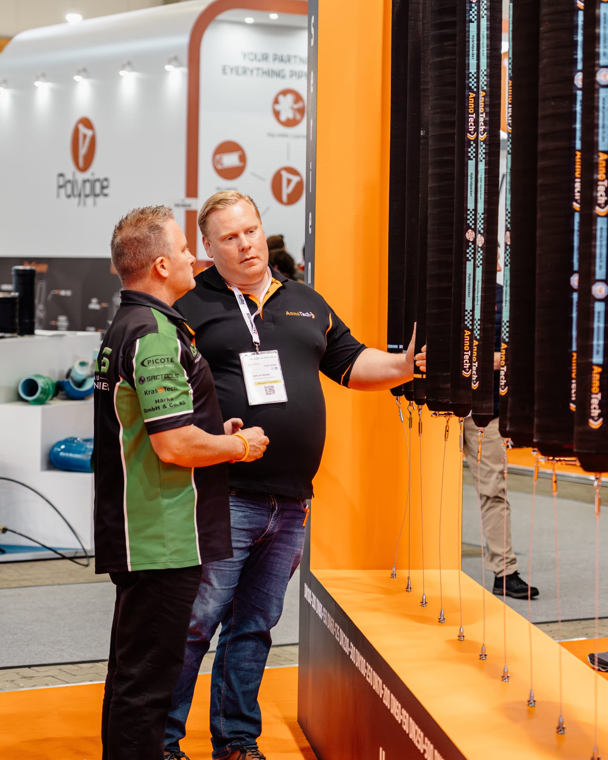 AnnoTech Mitarbeiter in Polo-Shirt erläutert Besucher Produktdetails am Messestand