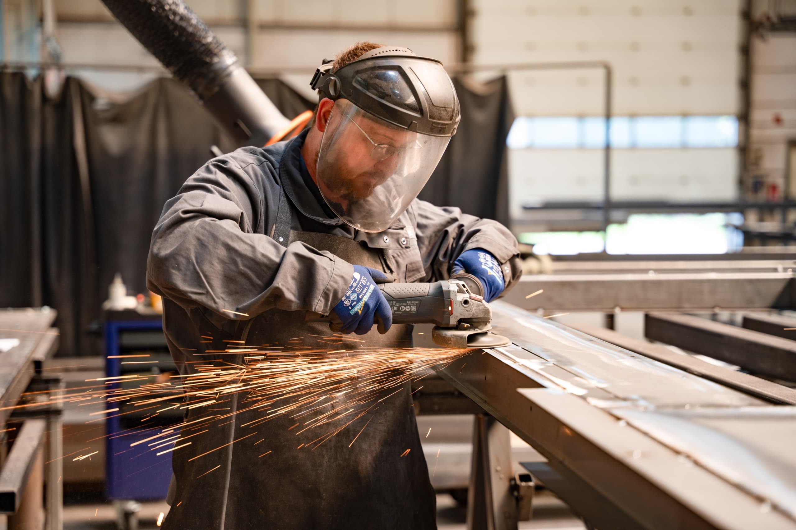 AXA Schlosser schleift Metallprofil mit Winkelschleifer, Funken sprühen
