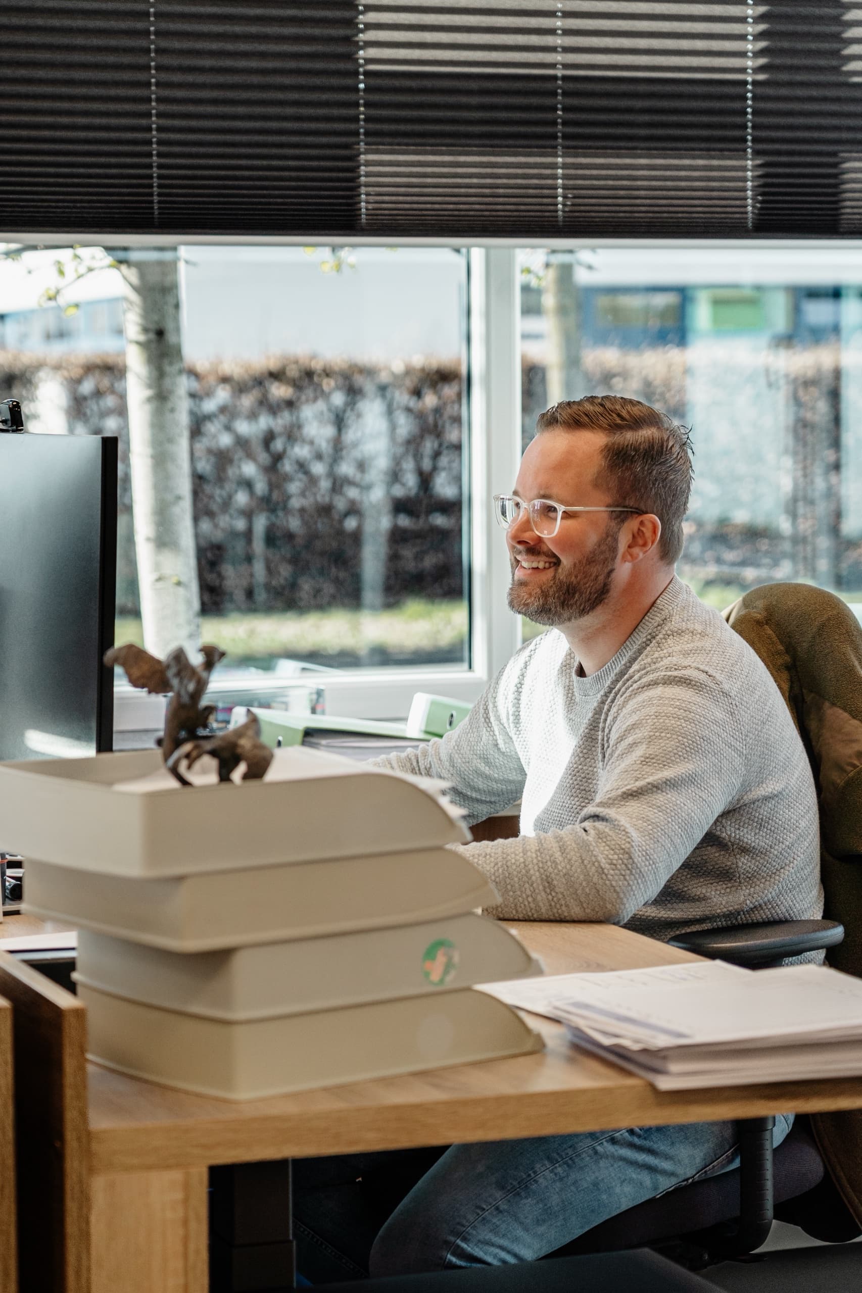 DM-Eichenauer Büroangestellter lächelt am Schreibtisch mit Monitor