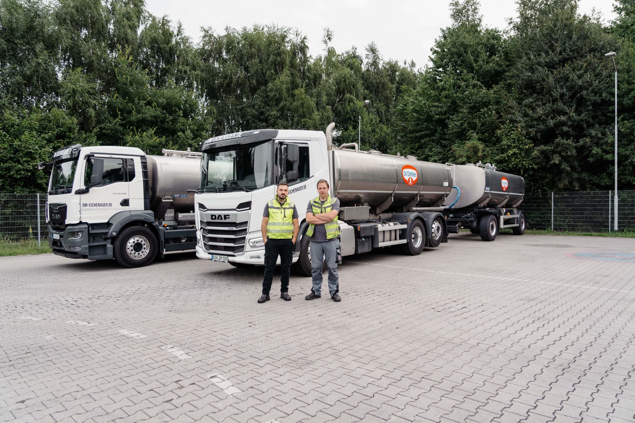 Zwei DM-Eichenauer Fahrer vor DAF- und MAN-Tanklastwagen auf dem Betriebshof
