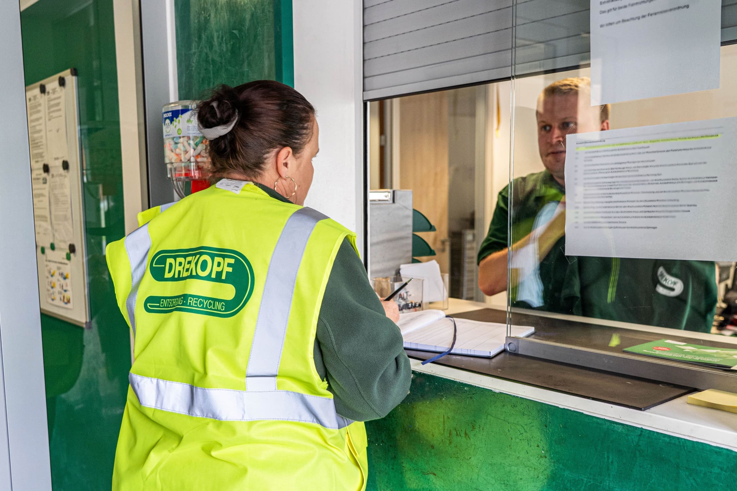 Drekopf Mitarbeiterin in gelber Warnweste am Anmeldeschalter des Recyclinghofs