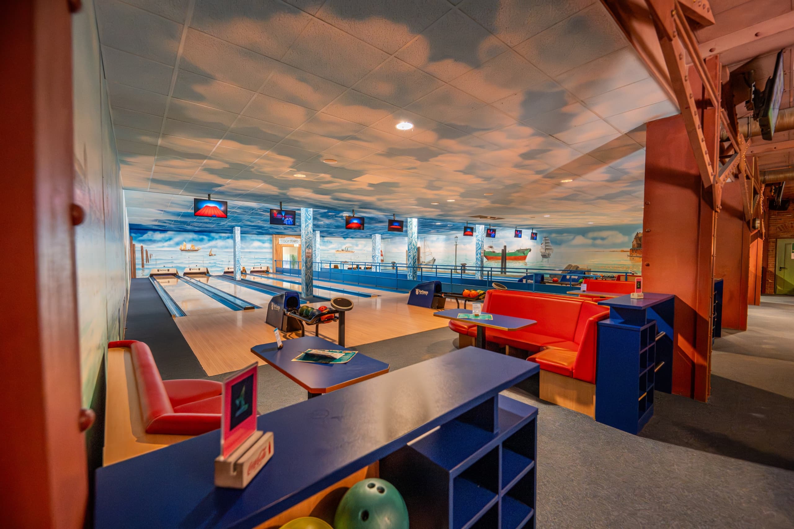 Bowlingbahn im Schloss Dankern mit maritimem Hafenmural und blauen Sitzen, Seitenansicht