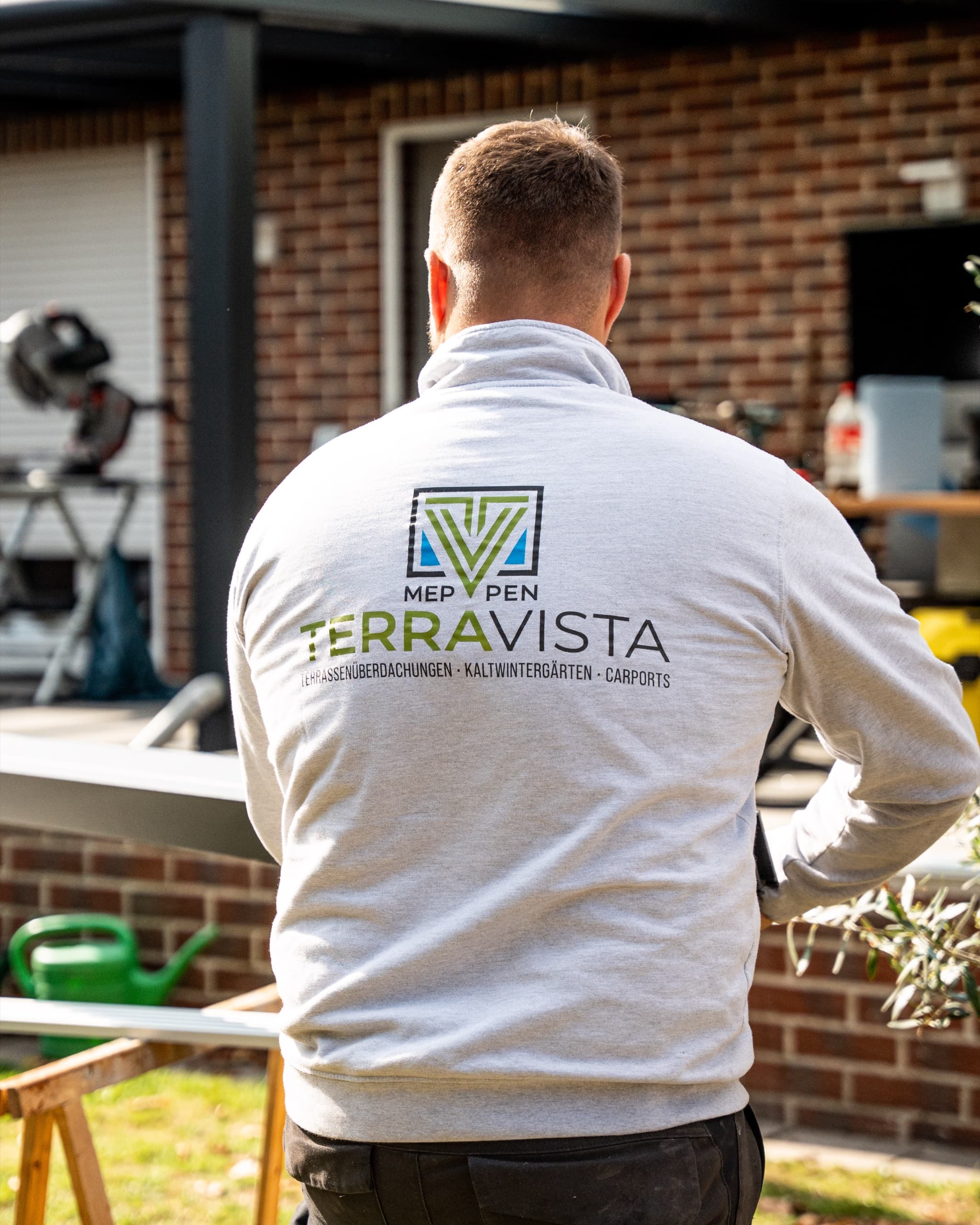 Terravista Meppen Monteur von hinten mit TERRAVISTA-Logo auf grauem Sweatshirt an Baustelle